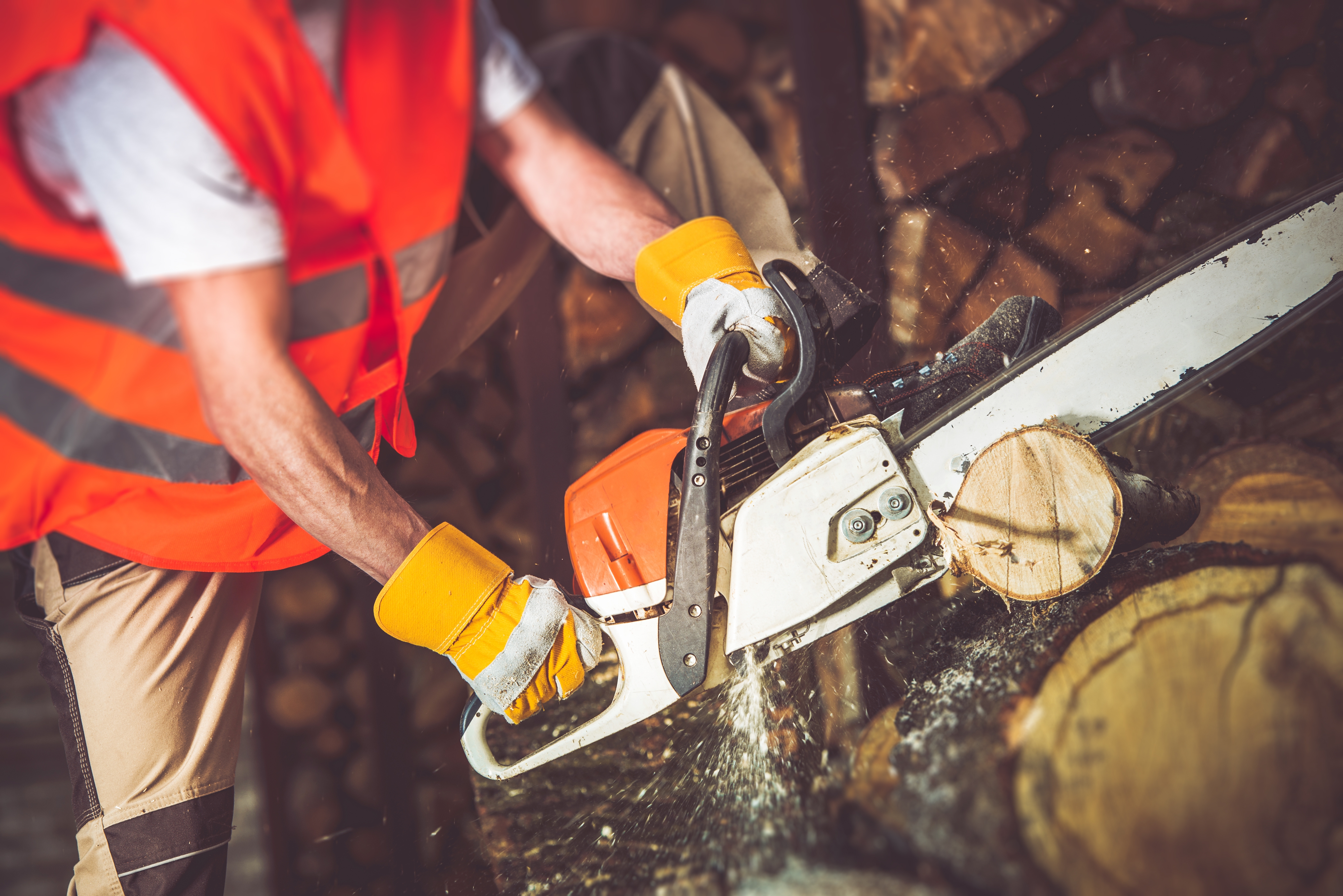 man using chainsaw to cut log